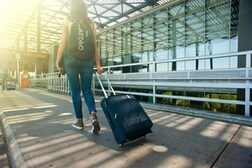 A young woman with a rucksack and trolley on a platform